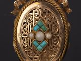 a close up of a gold locke with a turquoise stone in it