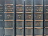 plusieurs vieux livres sont alignés sur une étagère dans une bibliothèque