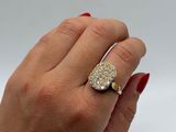 a woman ' s hand holding a gold and white diamond ring