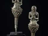 deux statues de Bouddha en bronze, assises sur un socle noir