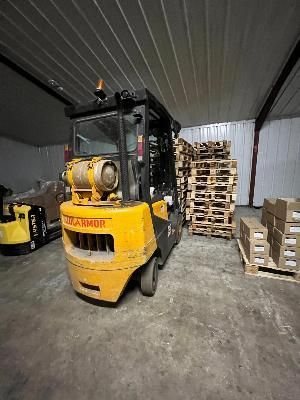 un chariot élévateur dans un entrepôt où se trouvent des palettes de bois