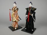 two figurines of asian women dressed in traditional clothing and holding swords