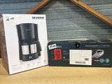 two boxes of coffee machines sitting on top of a wooden table