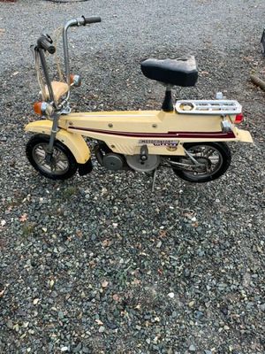 un petit scooter jaune garé sur le gravier