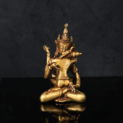 une statue en or représentant une personne assise sur une surface noire