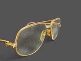 gold rimmed sunglasses on a gray background with a reflection of the lens