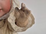 a close up of a doll wearing a bonnet and dress