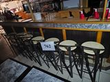 un bar avec de nombreux tabourets et une enseigne accrochée au comptoir