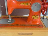 a red sewing machine sitting on a wooden table