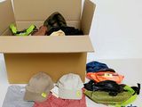 une boîte en carton remplie de vêtements et de chapeaux, posée par terre
