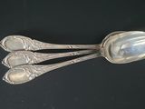 two silver spoons on a black surface with a black background