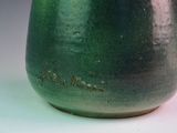 a close up of a green vase on a white surface