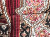 a close up of a red, black, and white blanket on a wooden floor