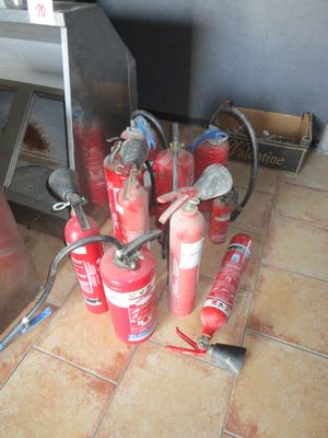 many fire extinguisors sitting on the floor next to a stove