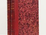 un vieux livre à la couverture rouge posé sur une table blanche