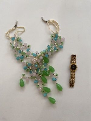 a picture of a necklace and a watch on a table