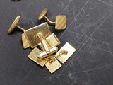 a pair of gold cufflinks and a pair of cufflinks on a table