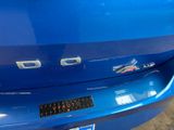 the rear end of a blue car with a sticker on it ' s bumper