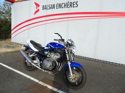 une moto bleue garée sur un parking, près d'un mur