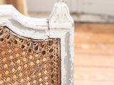a white chair with a wicker back and a wooden seat