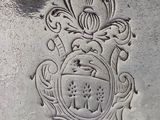 a close up of a silver vase with a crest on it