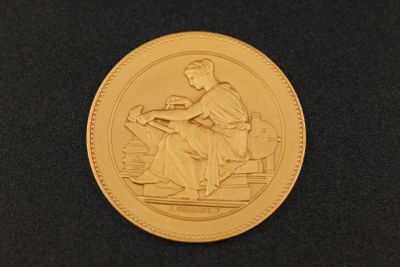 un gros plan d'une pièce d'or sur laquelle figure une femme assise sur un banc