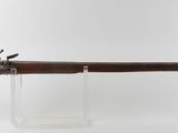 un vieux fusil au canon en bois, posé sur un socle transparent