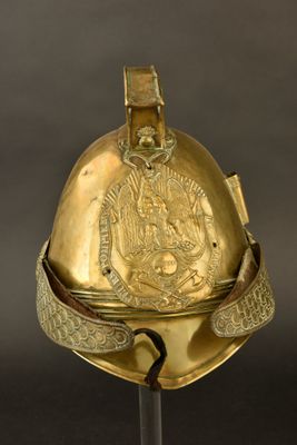 un vieux casque orné d'une décoration dorée, posé sur un socle