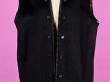 un gilet noir posé sur un mannequin, devant un fond rose