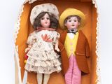 two dolls that are in a box on a white surface