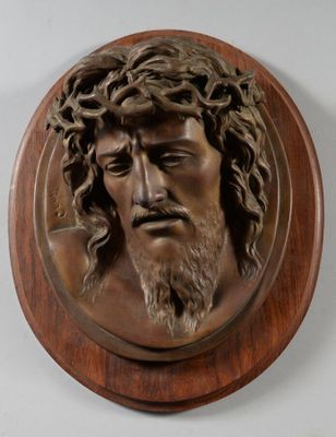 une image représentant une tête de Jésus en bronze sur une plaque en bois