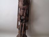 une vieille sculpture en bois représentant un homme assis sur un bloc de bois