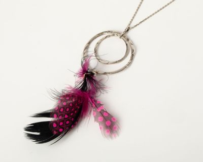 un gros plan sur un collier auquel est suspendue une plume