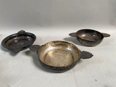 trois plats anciens en métal argenté posés sur un plan de travail blanc