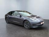 a grey tesla model 3 parked in a showroom