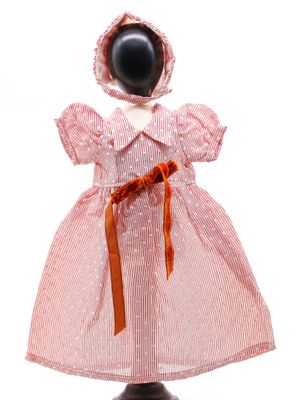 un gros plan d'une poupée portant une robe rose et un bonnet