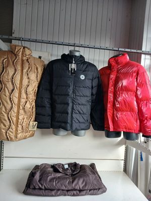 three jackets hanging on a clothes rack in a room