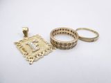 two gold rings and a gold pendant on a white surface
