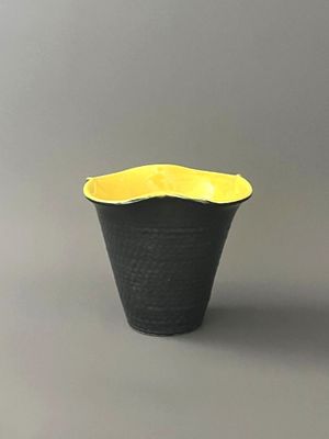 a black and yellow vase sitting on a gray surface