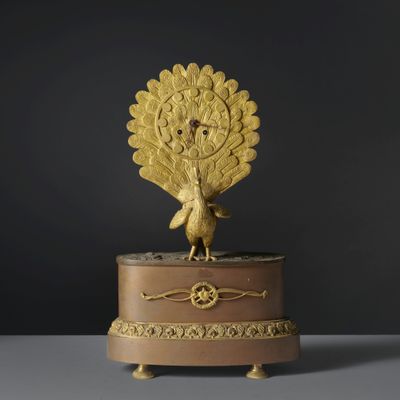 une horloge plaquée or surmontée d'un paon