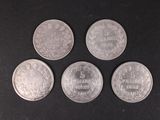six different coins are arranged in a row on a black surface