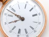 a gold pocket watch with roman numerals on the face