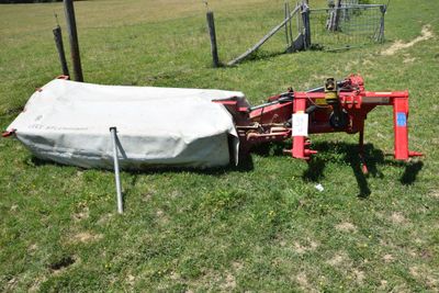 a tractor that is sitting in the grass with a tarp on it