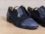 pair of men ' s shoes on a wooden table with a white wall in the background