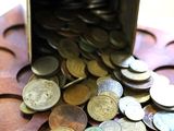 a metal container filled with coins on top of a wooden table