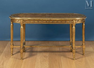 une table dorée avec un plateau en rotin posée sur un parquet