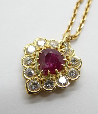 une photo d'un pendentif en rubis et diamants monté sur une chaîne en or