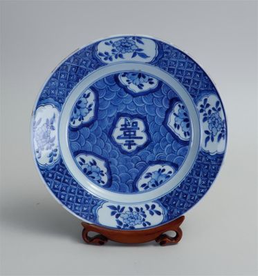 Assiette chinoise bleue et blanche ornée d'un motif de dragon, posée sur un socle