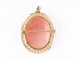 an image of a gold and coral colored broochle pendant on a white background