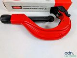 a red pipe cutter on a white table next to a box